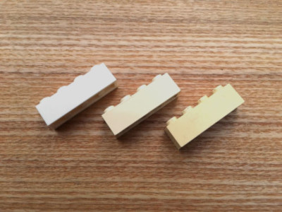 Three LEGO bricks with various discolorations before cleaning